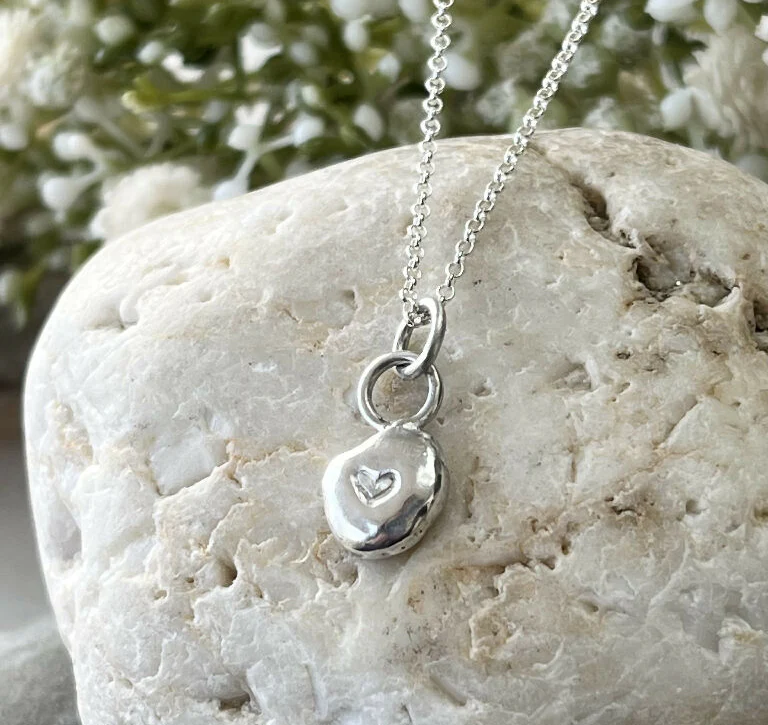A handmade recycled fine silver hand stamped heart pebble pendant necklace.